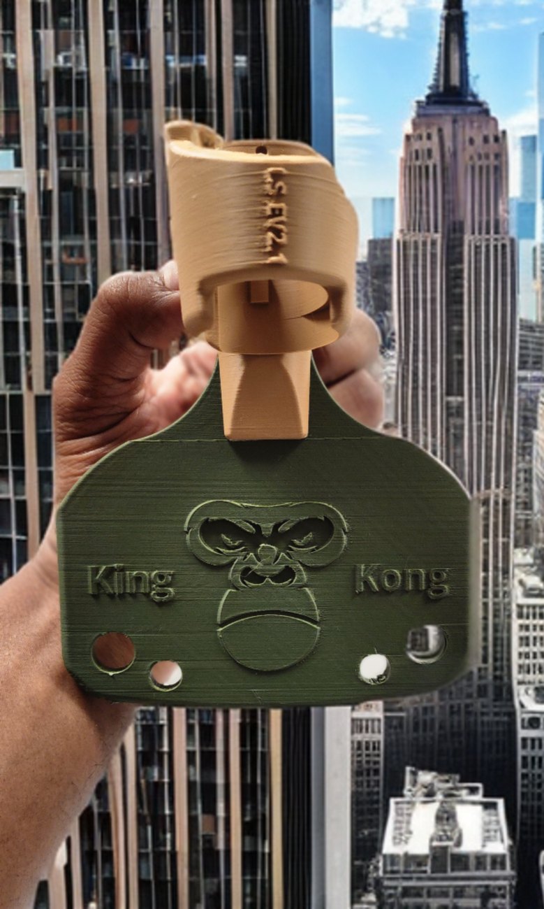 Olive-green King Kong themed Ls4life adapter held up against a city skyline